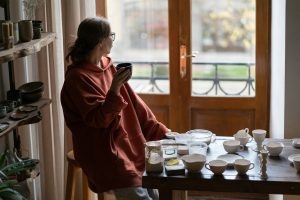 Successful pensive woman owner of small business selling goods made in pottery shop drinking tea